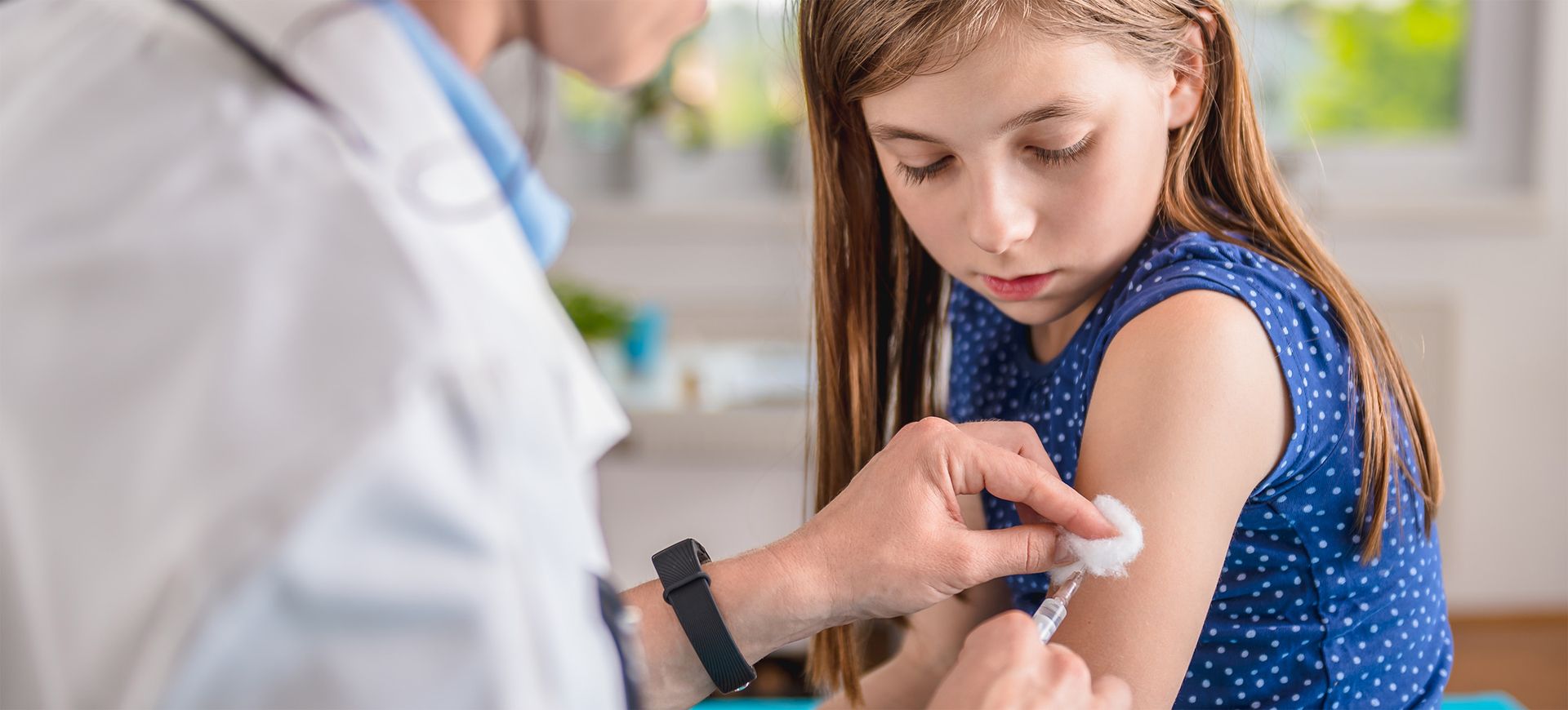 Mädchen erhält Impfung beim Kinderarzt, Schutzimpfungen für Schulkinder in der Seewinkel Kinderordination